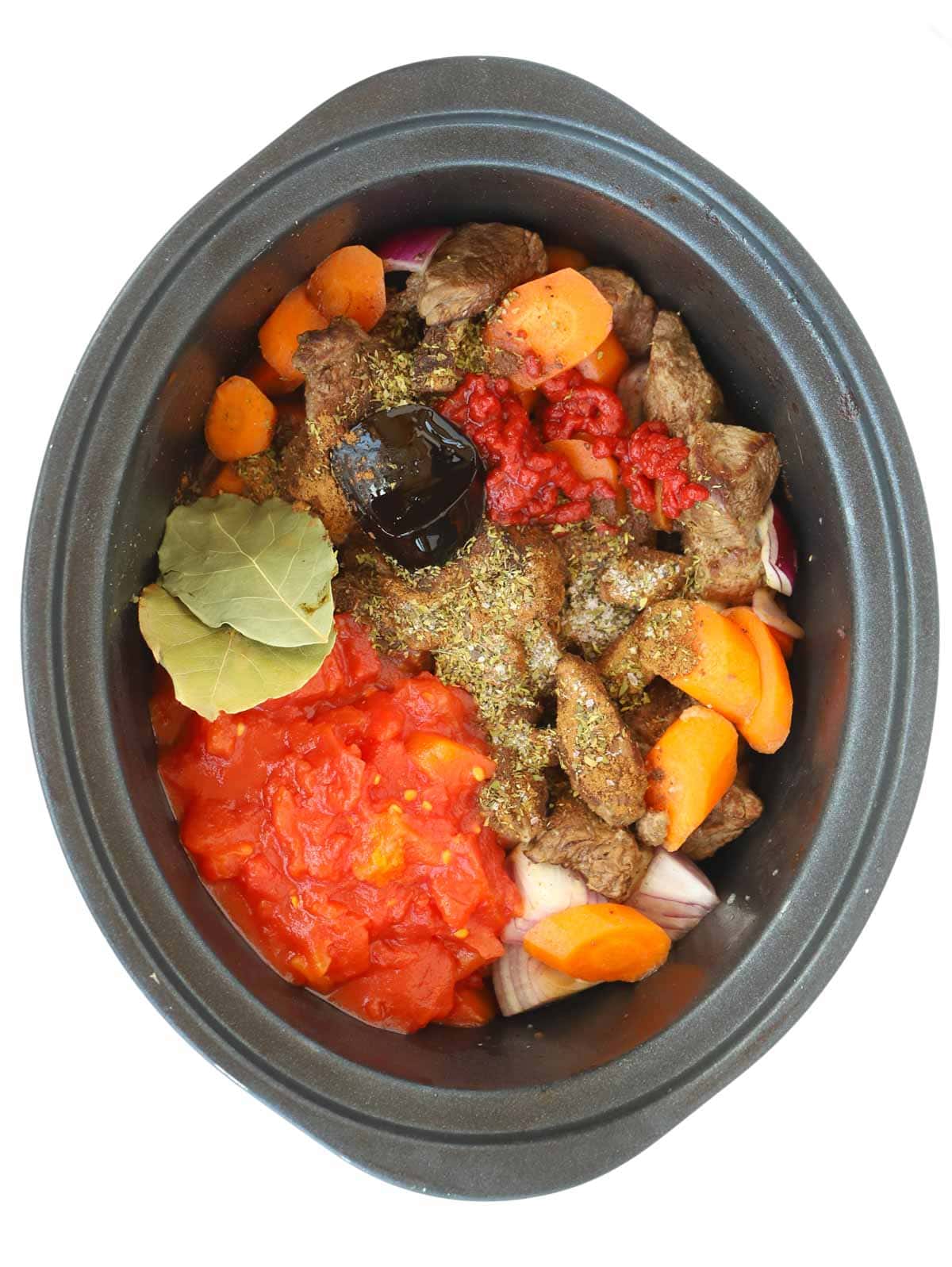 The raw ingredients for making a Greek stew, Beef Stifado, in a slow cooker, ready to be cooked.