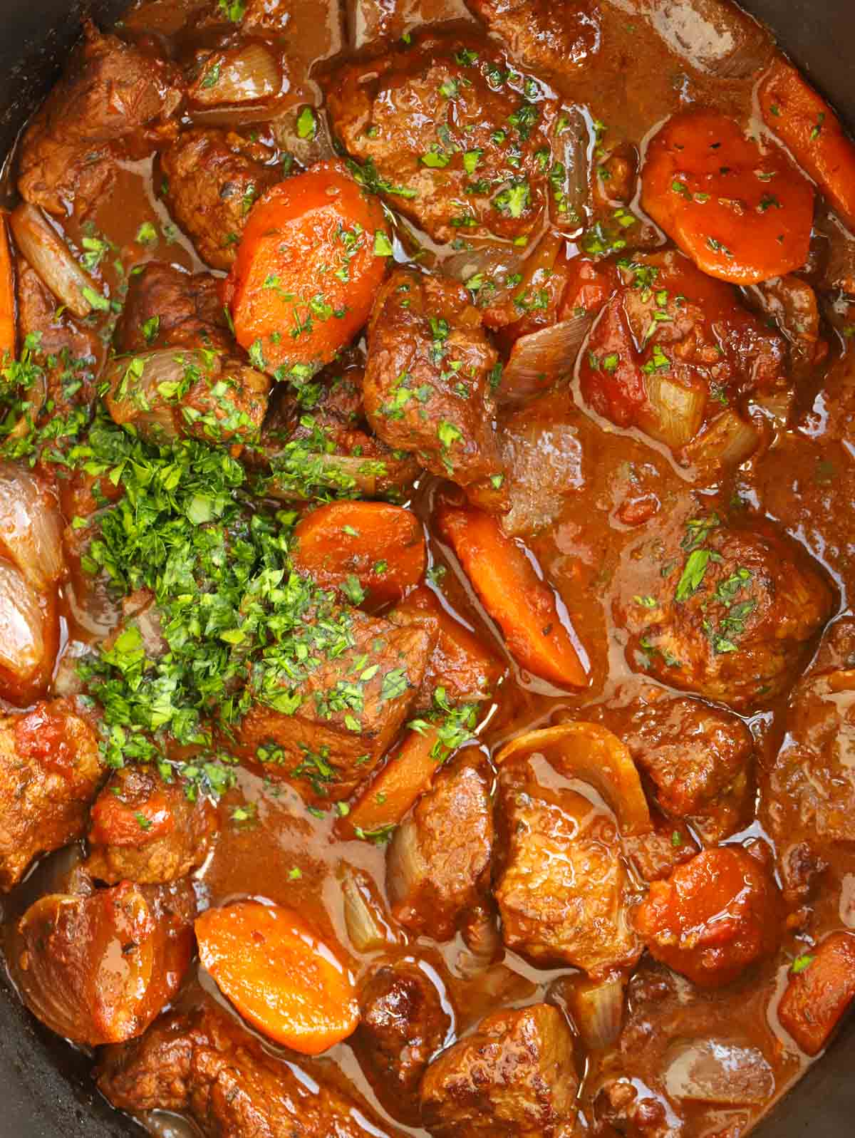 A close up of a Beef Stifado Greek stew with carrots, onions and a rich beef gravy.