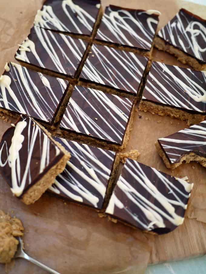 A board with squares of Peanut Butter Bars with chocolate topping, ready to eat.