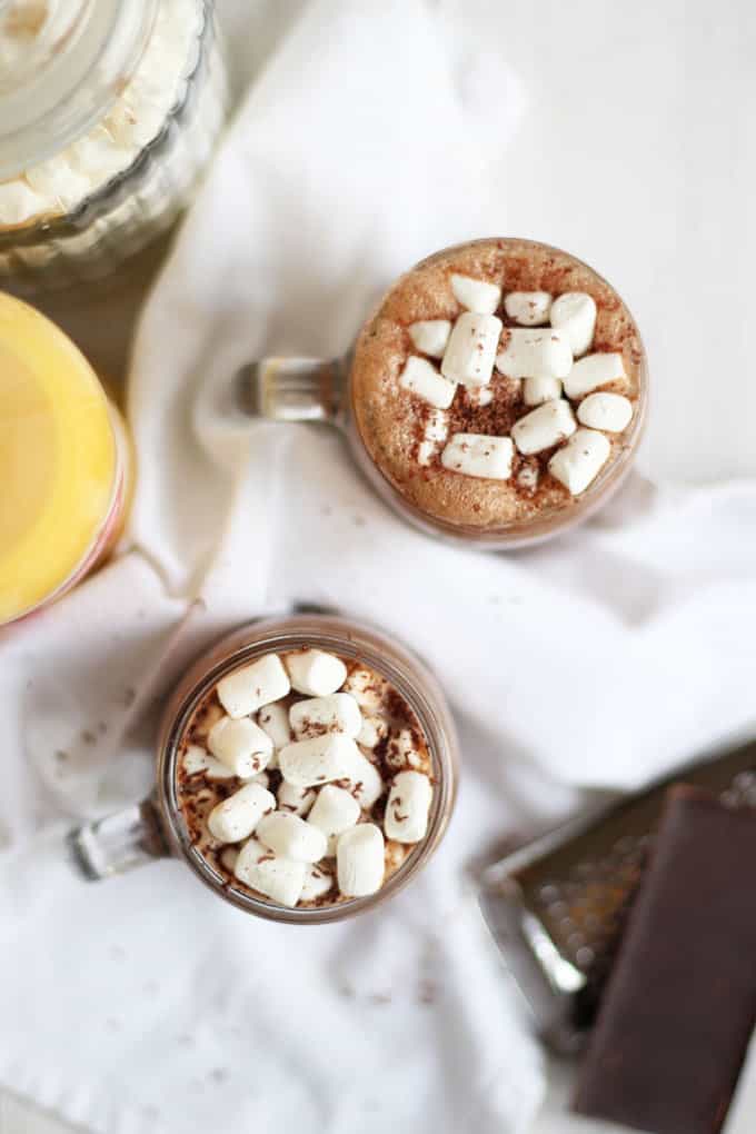 A bird's eye view of two mugs of hot chocolate with Advocaat, topped with cream and marshmallows.