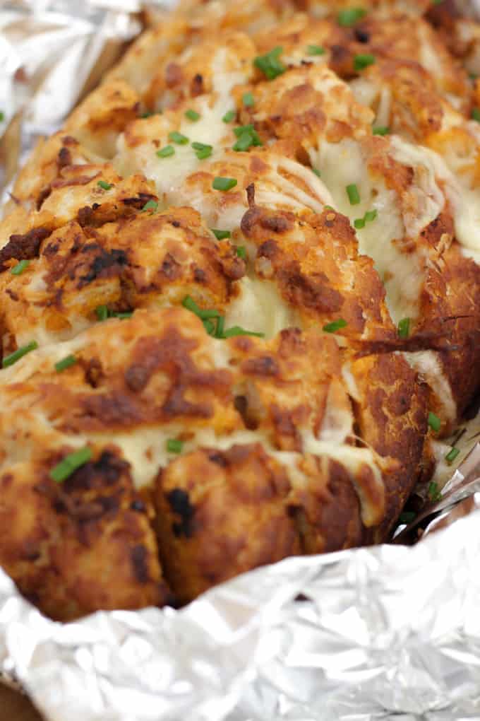 Cheesy Pesto Garlic Pull Apart Bread - A cheese filled treat. The perfect side dish for dinner or snacking. Pesto adds a depth of flavour to this pull apart bread with the mountains of melting mozzarella cheese.