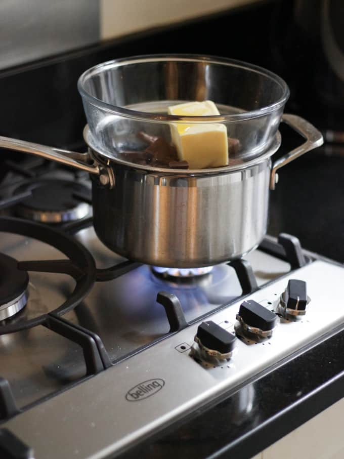 A saucepan on a gas hob topped with a glass bowl with chocolate and butter and golden syrup in to melt in a Bain Marie.