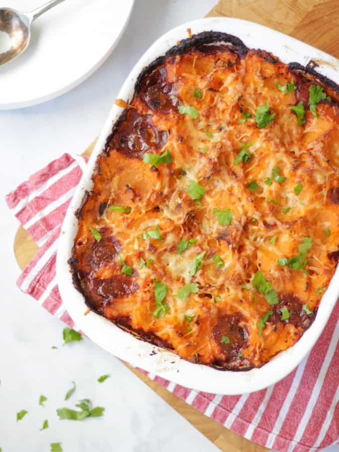 Overhead photo of sweet potato cottage pie in a white dish on a red and white tea towel.