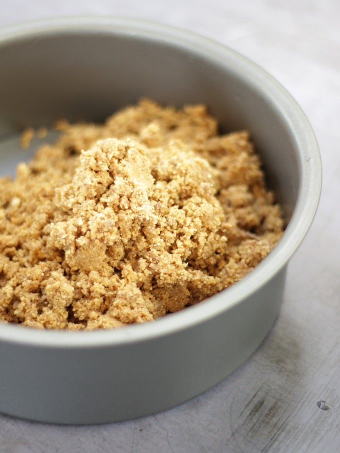 A round tin with a crumbled biscuit base inside, for step 1 in the recipe for Rocky Road Cheesecake.