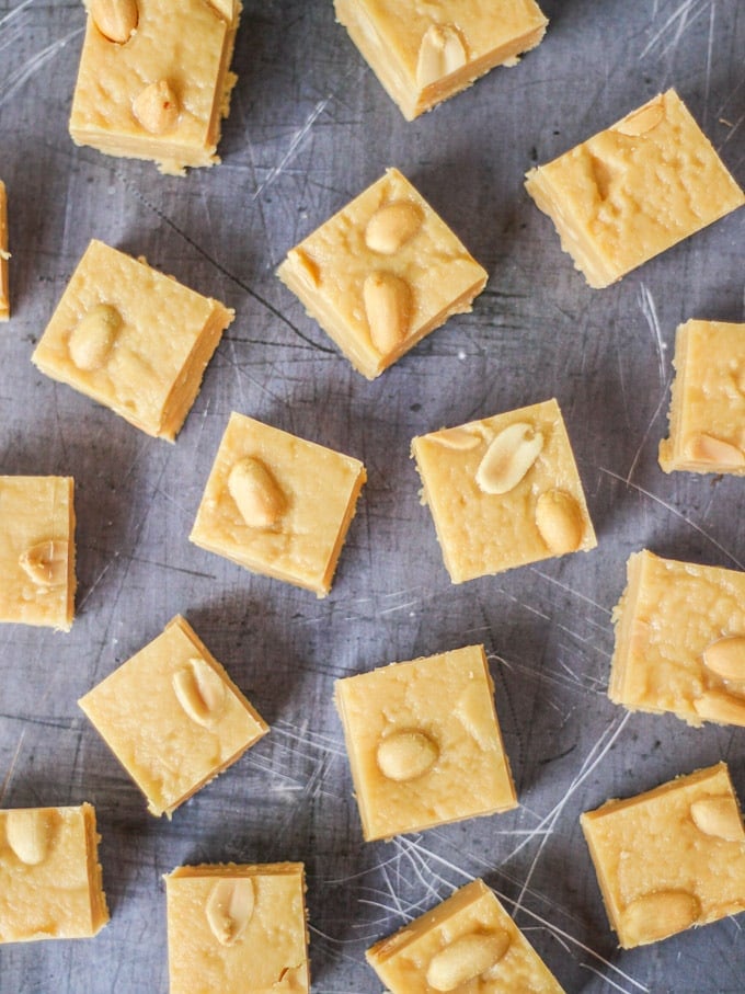 Overhead photo of microwave peanut butter fudge cubes with salted peanuts on top on grey background.