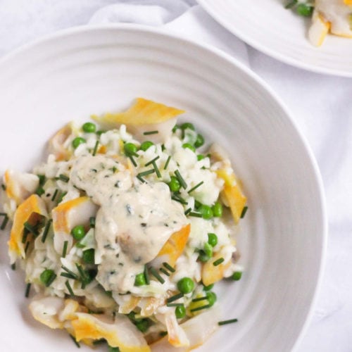 The Saucy Fish Co Smoked Haddock recipe for Smoked Haddock Risotto in a white Sophie Conran bowl topped with chives on white marble background.