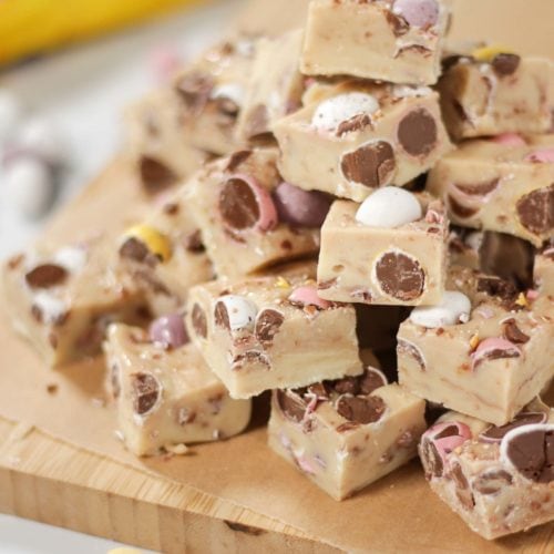 Pile of mini egg fudge with bag of Cadburys Mini Eggs in the background.