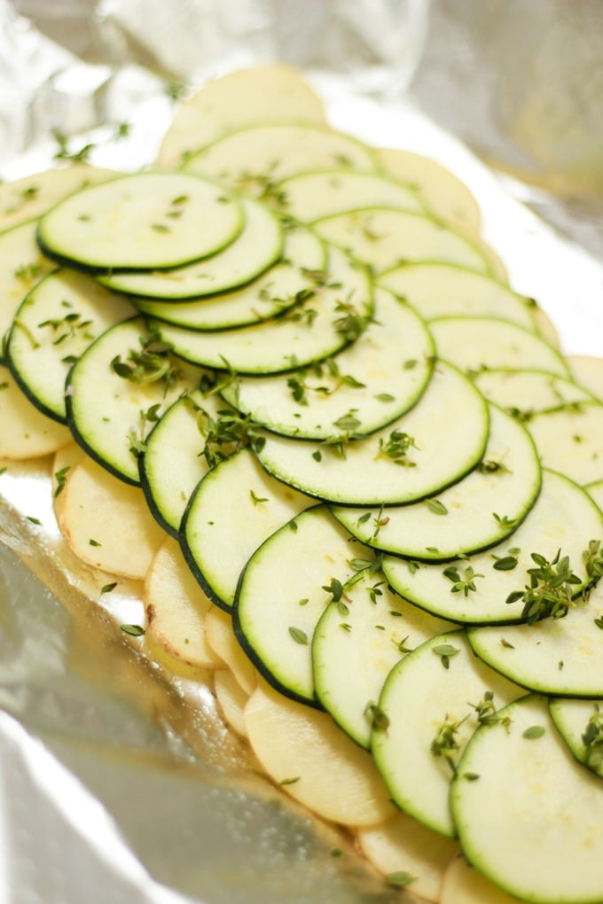 Slices of raw potato and courgette layered on foil.