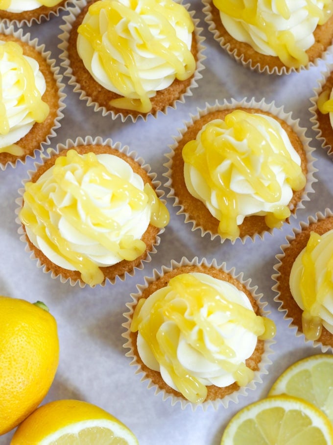 Tops of lemon cupcakes with zesty moist drizzle.