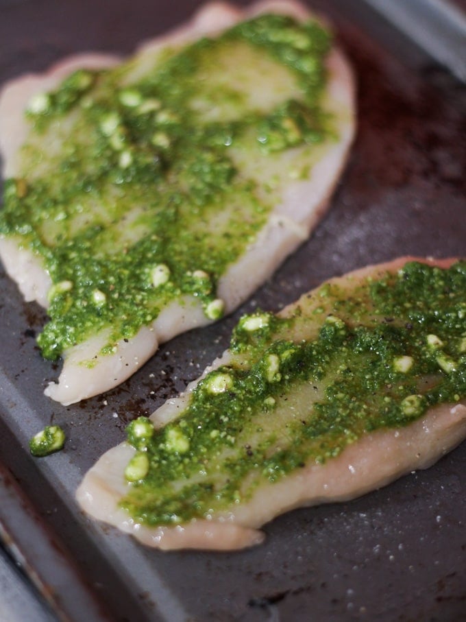 raw meat with herb paste on a baking tray