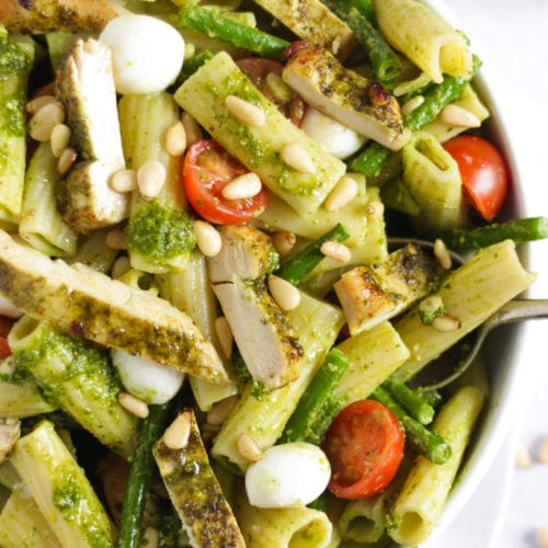 Chicken pesto pasta bake with tomatoes and green beans in a white bowl