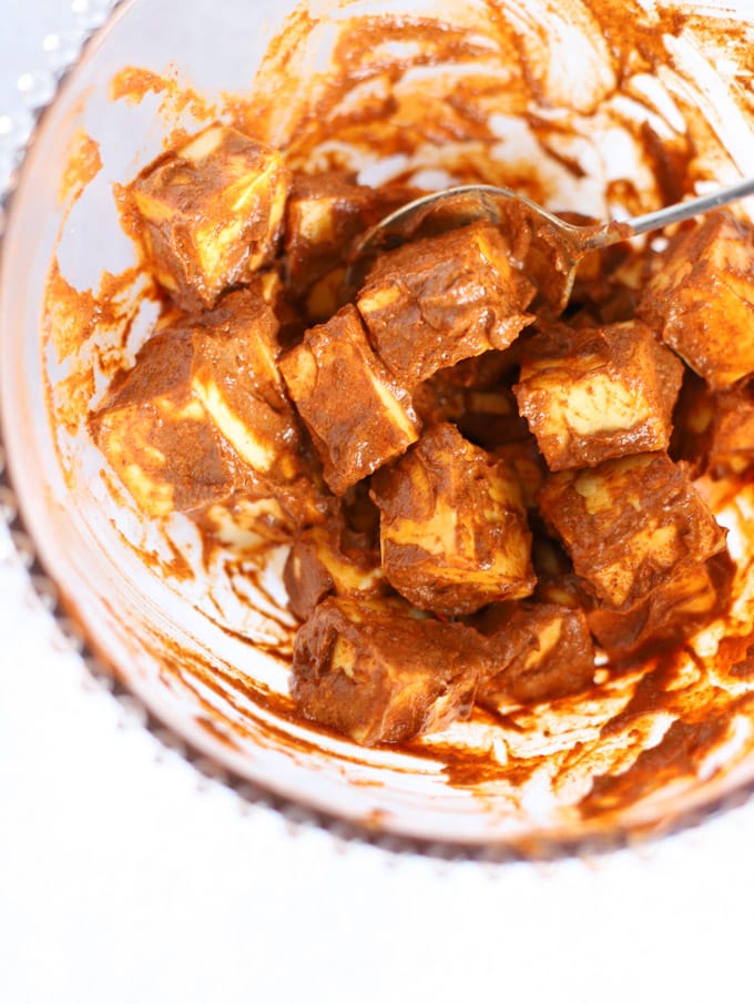 Cubes of Indian cheese paneer coated in spices and yoghurt in a bowl for step 1 in the recipe for Paneer Tikka.