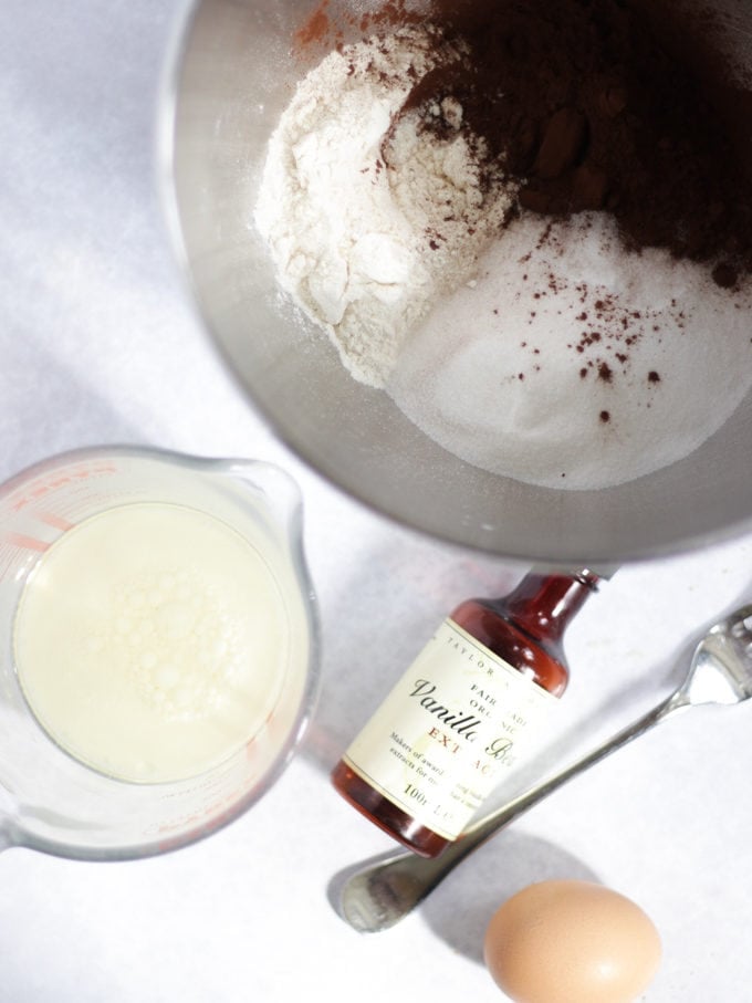 Bowl of flour, sugar and cocoa with a jug of egg, milk and oil for a chocolate cupcakes recipe.