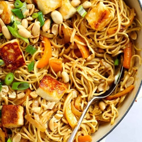 A fork in a big pan of noodles with halloumi and satay sauce for Peanut Butter Noodles.