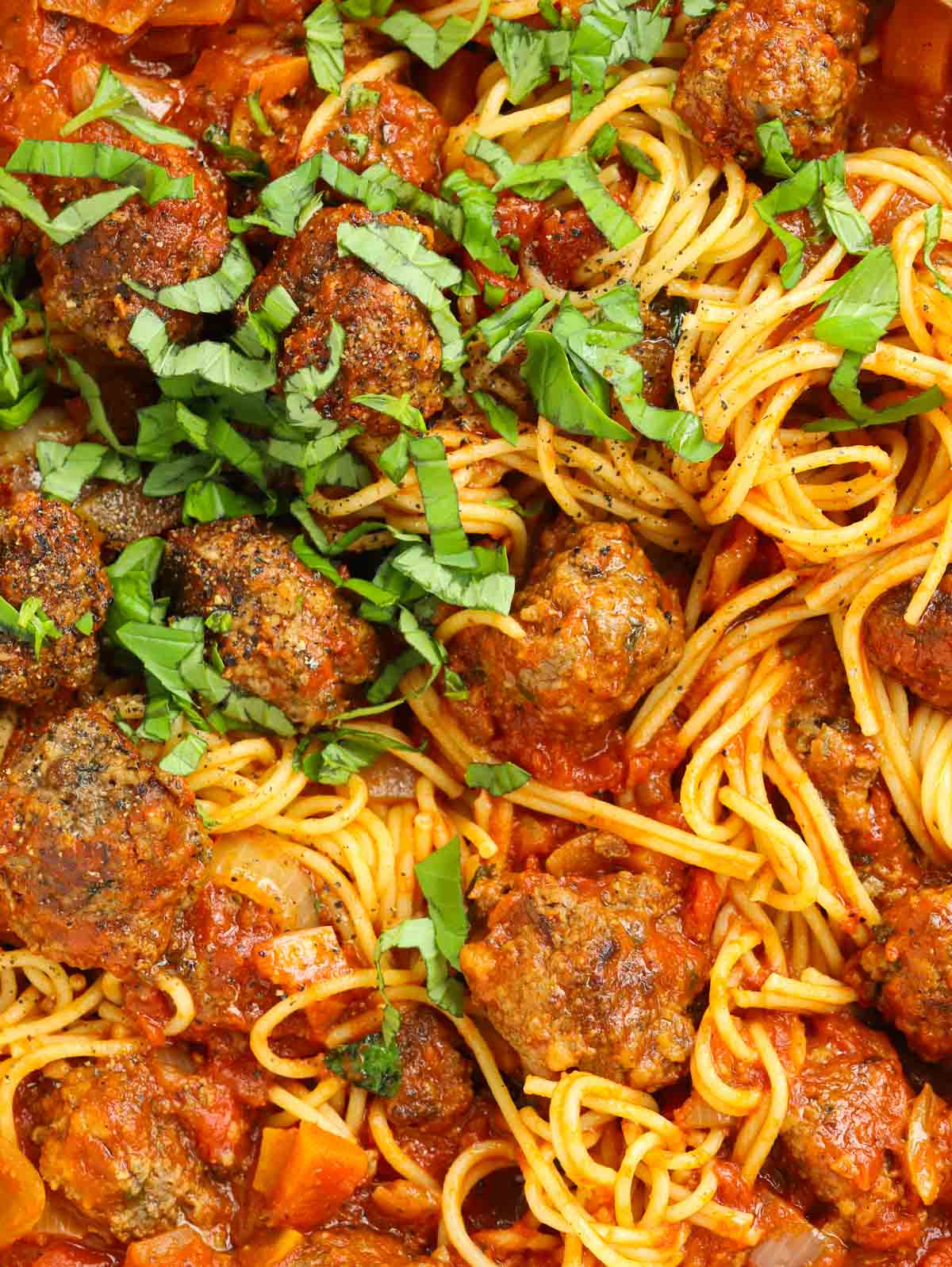 Close up of homemade meatballs made from scratch mixed with sauce and spaghetti.