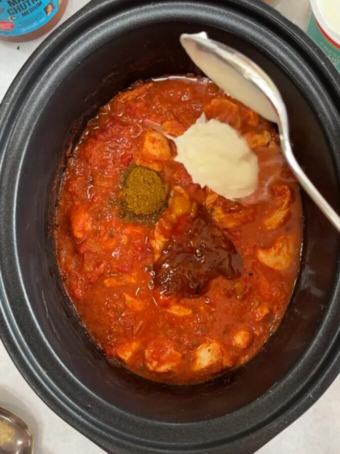 Step 2 of the recipe for slow cooker chicken tikka masala with a sauce and spices going in.