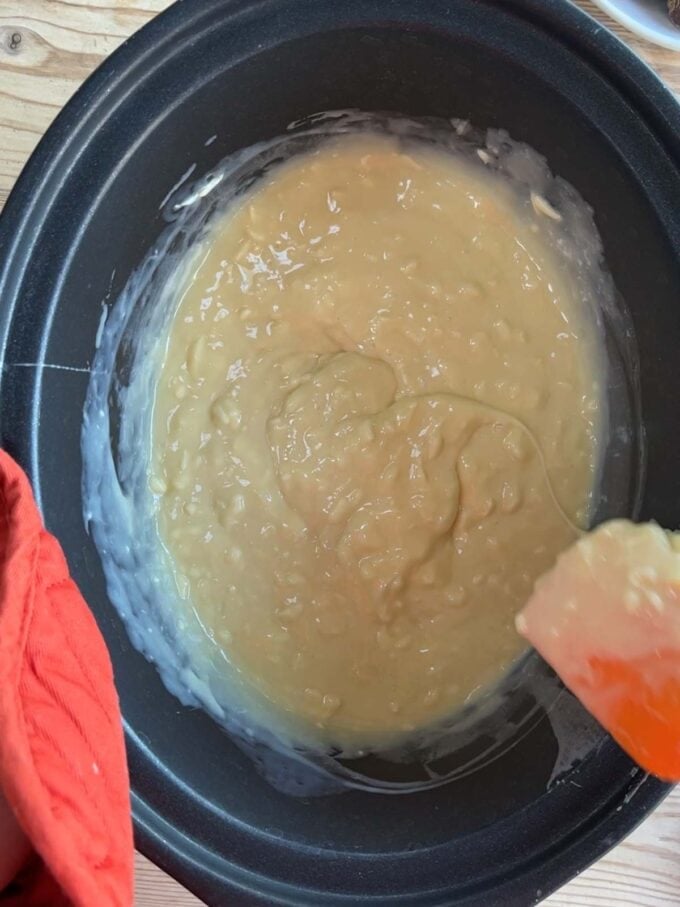 A slow cooker with melted white chocolate and condensed milk. Rolo Fudge recipe. Step 2.