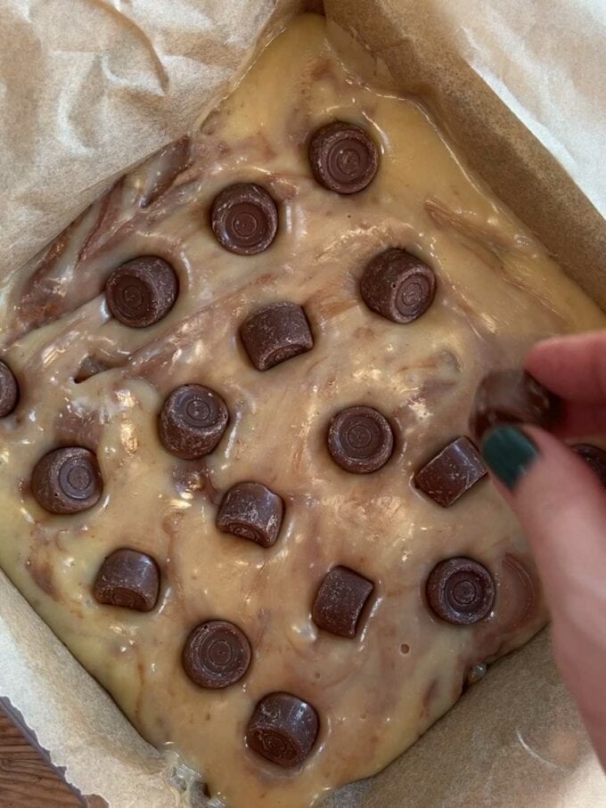 Chocolate mixture and rolos poured into a tray for the recipe Rolo Fudge. Step 4.