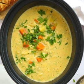 Bit slow cooker pan full of creamy slow cooker vegetable soup.
