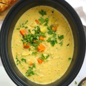 Bit slow cooker pan full of creamy slow cooker vegetable soup.