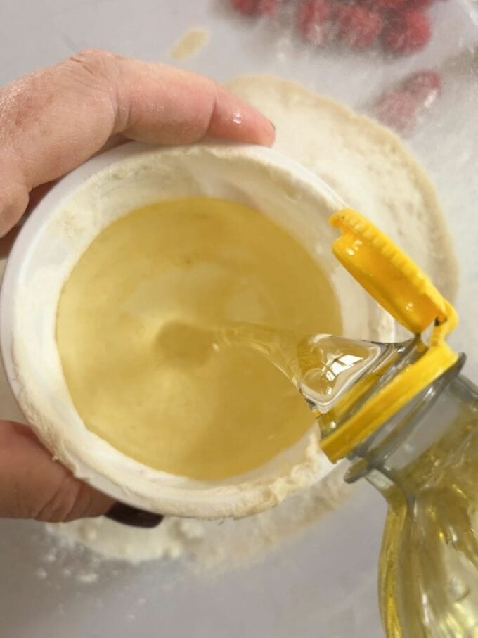 Measuring oil into a yoghurt pot for the recipe for Yoghurt Pot Cake.