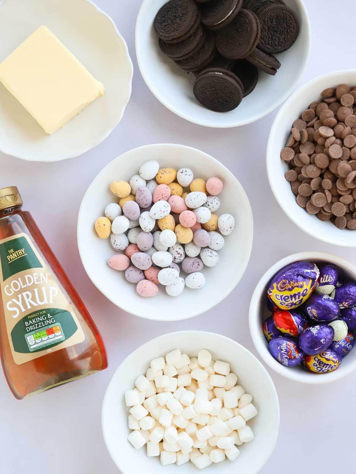 Ingredients on a counter, including chocolate, mini eggs, biscuits and golden syrup.