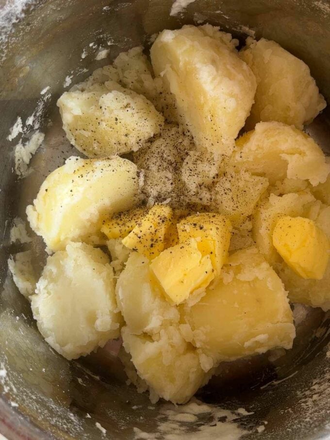 Boiled potatoes in a pan with knobs of butter.