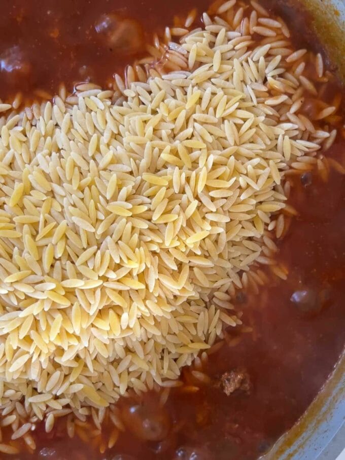 Dried orzo poured into a big pan of tomato sauce with mince beef.
