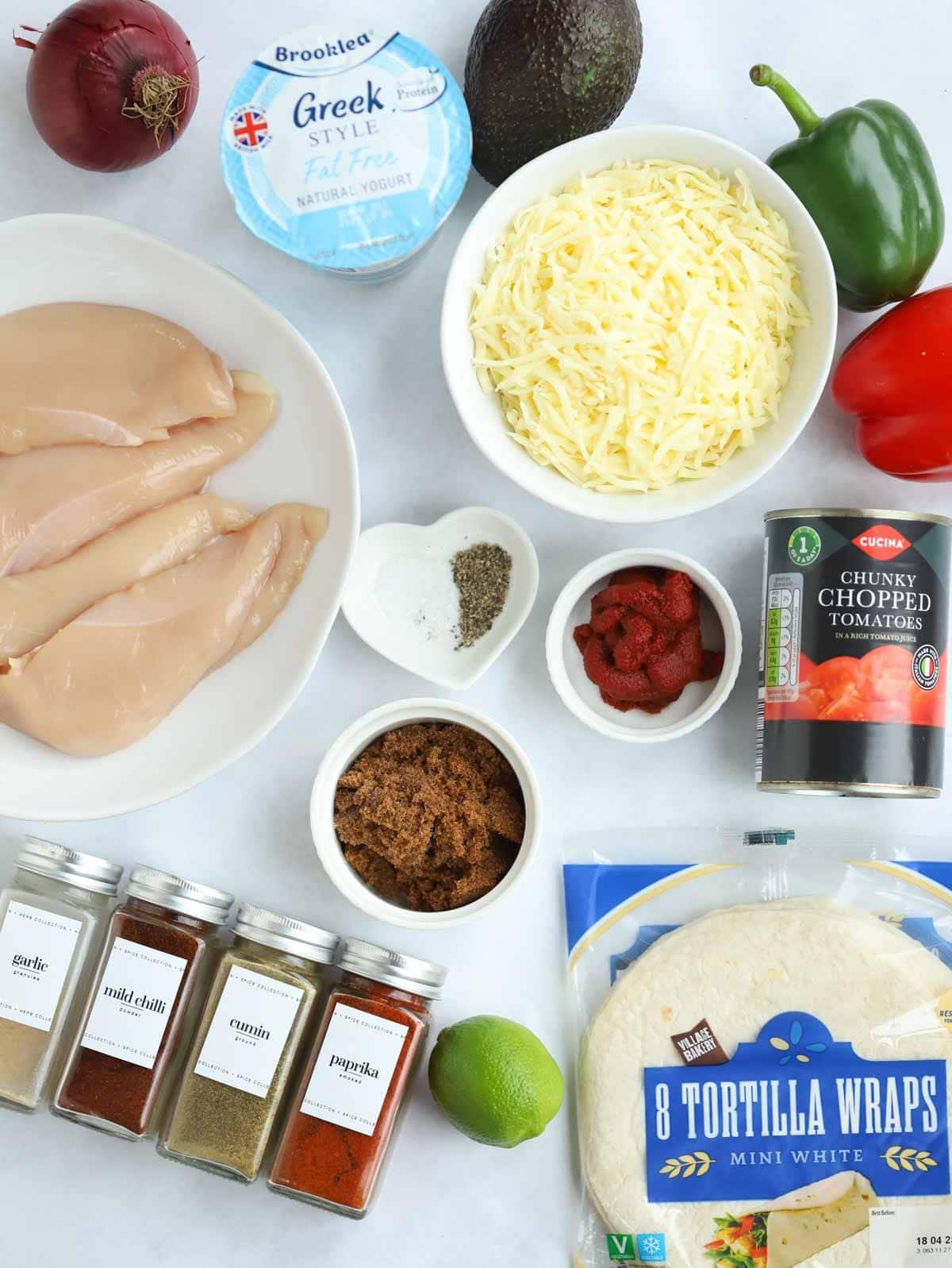 Ingredients laid out on a counter top, including chicken, cheese, tortillas and spices.