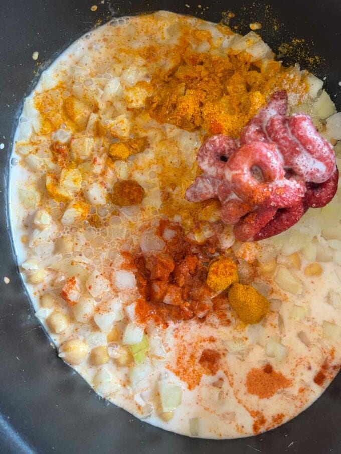 A slow cooker pan with coconut milk, chickpeas and spices, ready to be stirred.