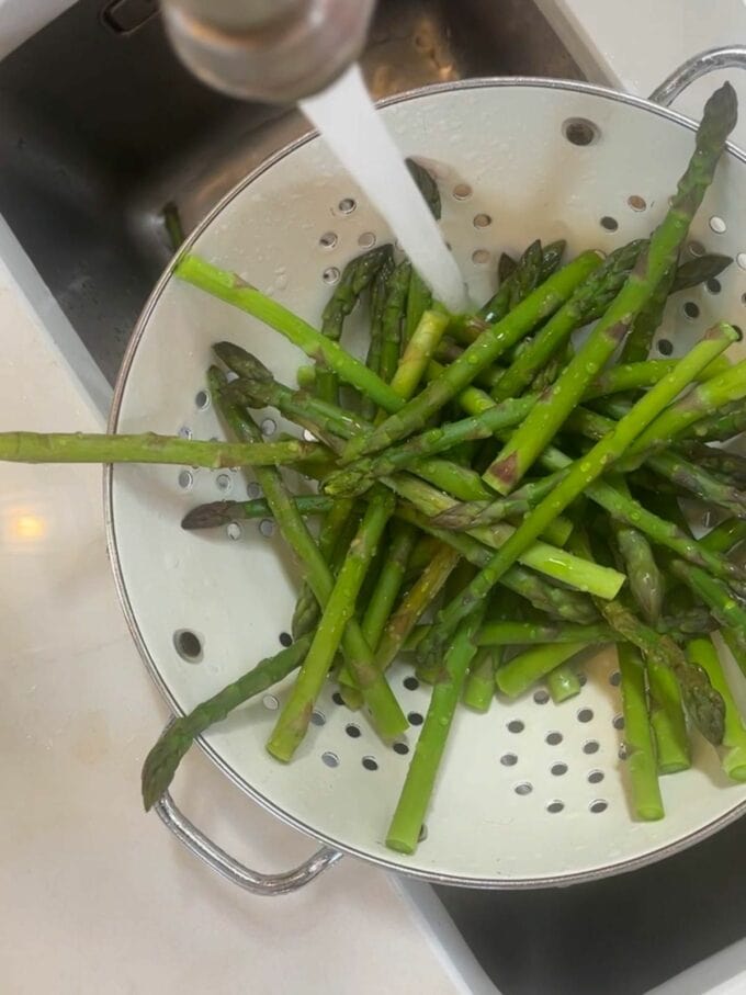 Step 1 in the recipe for Cheese & Asparagus in Puff Pastry Parcels. Cook and wash the asparagus.