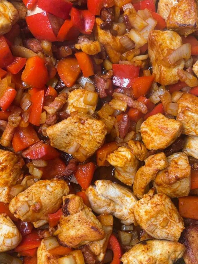 Vegetables in a pan with cooked chicken and bacon.