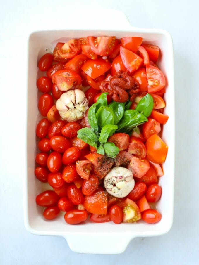 Tomatoes, garlic and basil in a roasting dish.