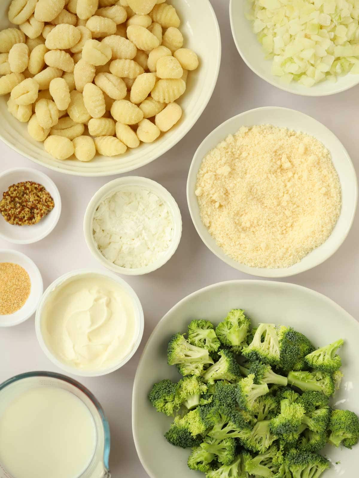 Ingredients of broccoli, parmesan, milk, cornflour and creme fraiche laid out on a counter.
