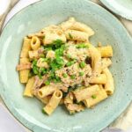 Quick and simple cream cheese pasta on a plate with peas and parsley on top. Ready to serve.