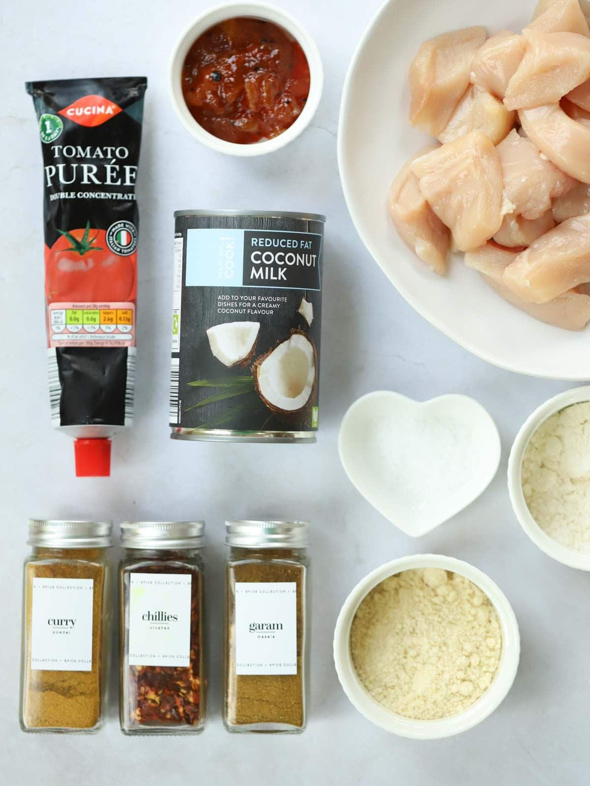 Ingredients laid out on a counter, including chicken, coconut milk and spices.