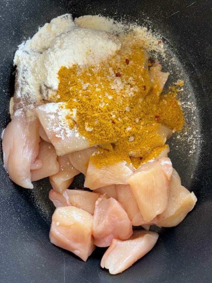 Chicken, flour and spices in a slow cooker pan.