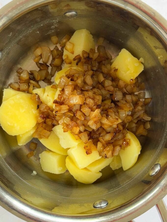 Potatoes and cooked onion in a bowl.
