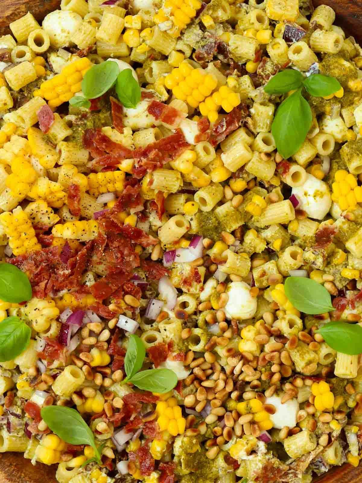 Pasta mixed with bacon bits, pesto, onion, mozzarella and pesto.