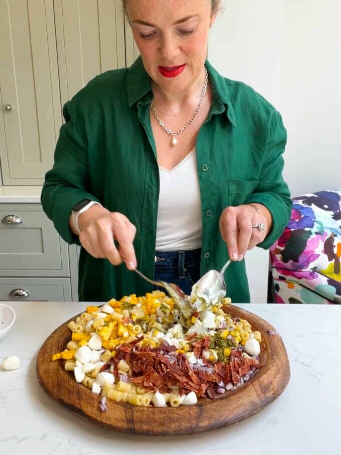Sarah Rossi of Taming Twins mixing a recipe for pesto pasta salad.