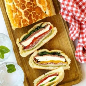 A stuff picnic loaf sliced and ready to eat on a chopping board.
