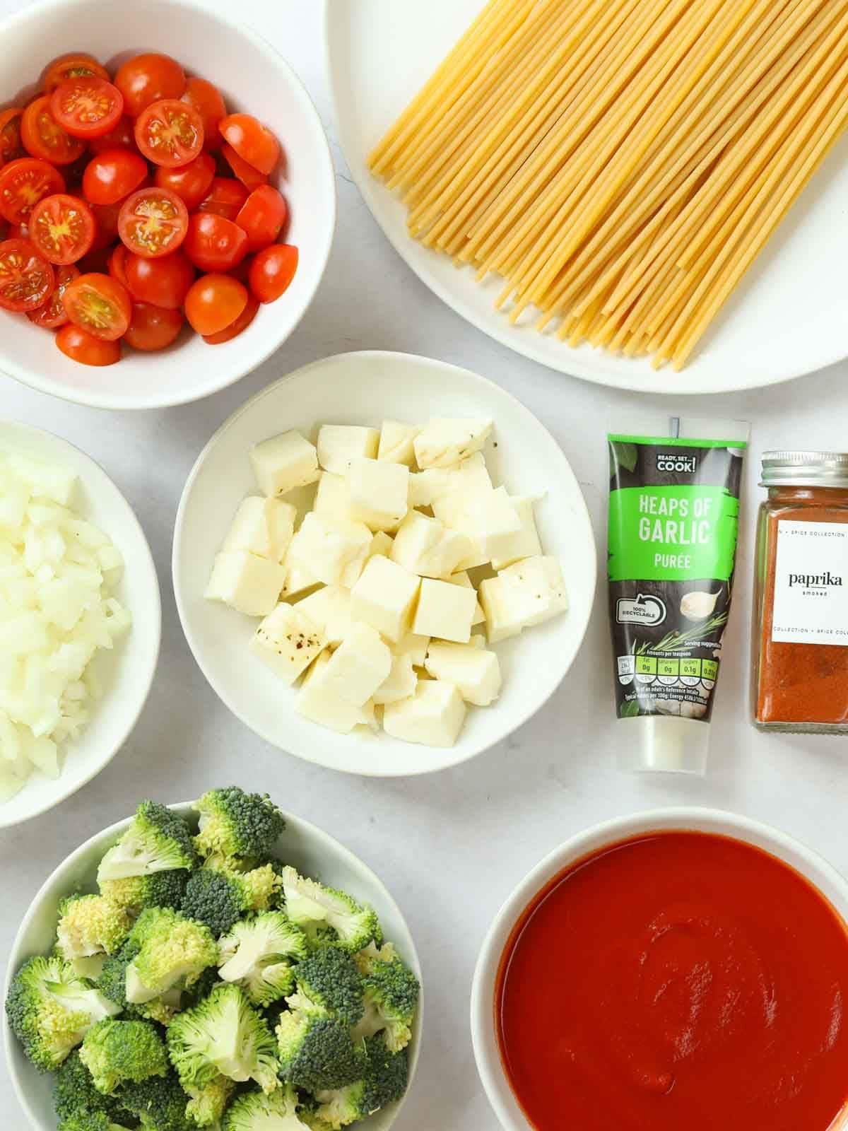 Ingredients laid out on a counter, including halloumi, tomatoes and pasta.