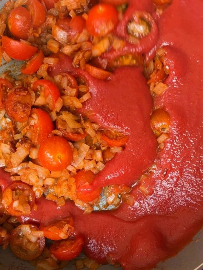 Pasta mixed with tomatoes and onion in a pan.