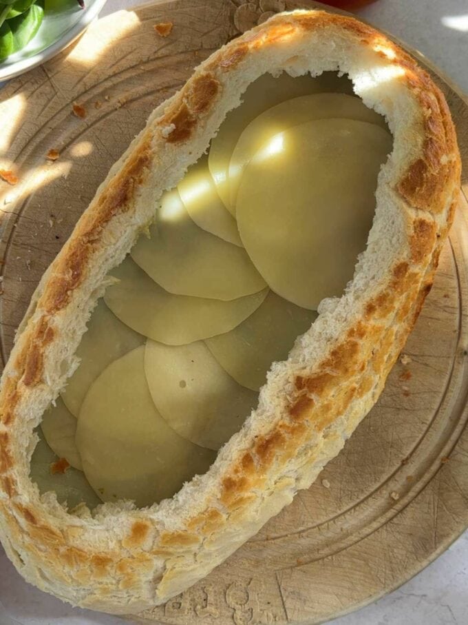 The next step to make a stuff picnic loaf is to add a layer of cheese.