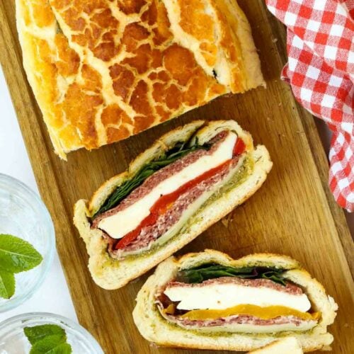 A wooden board with half a loaf of fresh tiger bread and sliced picnic loaf.