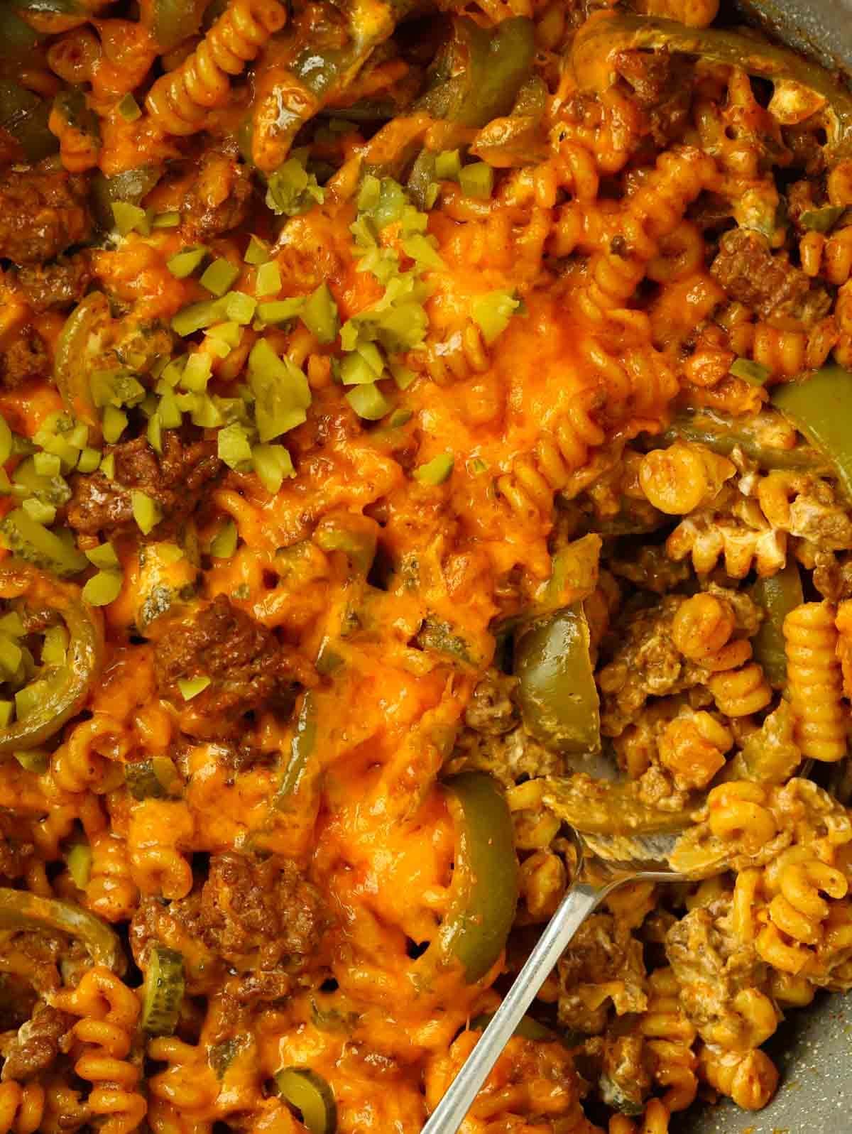 A close up of a pot of mince, pasta and cheese mixed together.