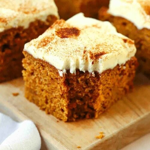 A square of pumpkin cake with a small bite taken out of the corner.