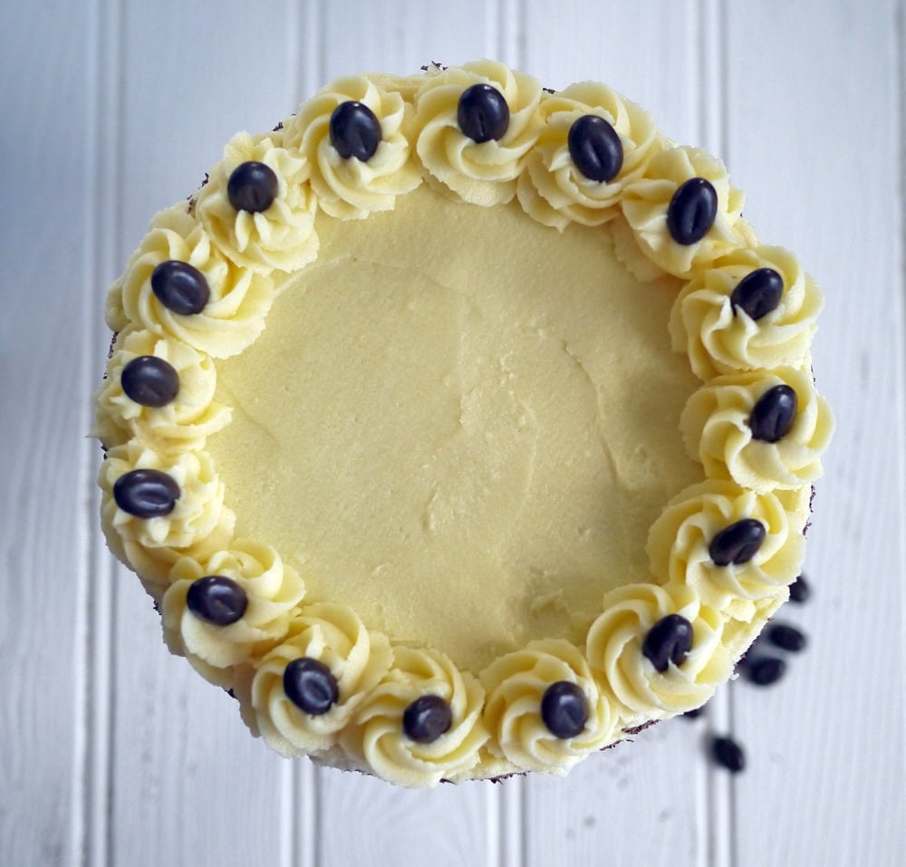 A bird's eye view of a Tiramisu Cake On a white background, with chocolate coffee beans on top.
