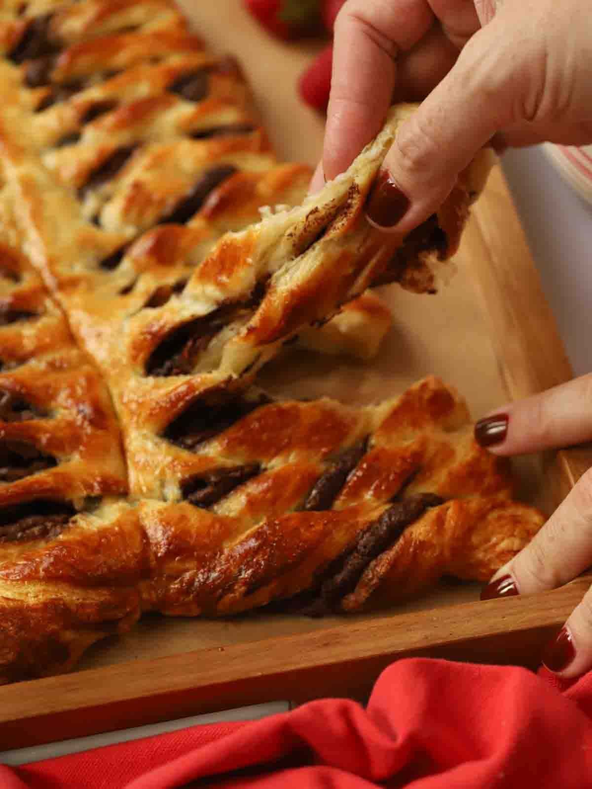 A close up of a hand pulling a swirl of Nutella Christmas Tree from a board.