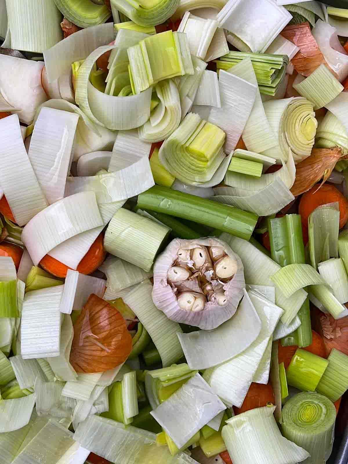 A close up of mixed chopped vegetables with garlic bulb in the middle for step 1 in the recipe for Vegetarian Gravy.